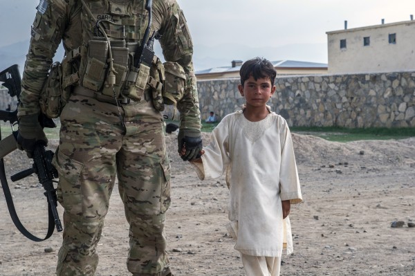 Soldier holding Afghani child's hand