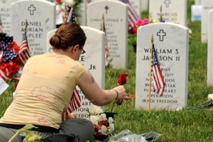 Wife putting a rose on her husband's tombstone
